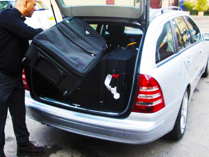 airport taxis driver loading a customers luggage into a mercedes airport taxi