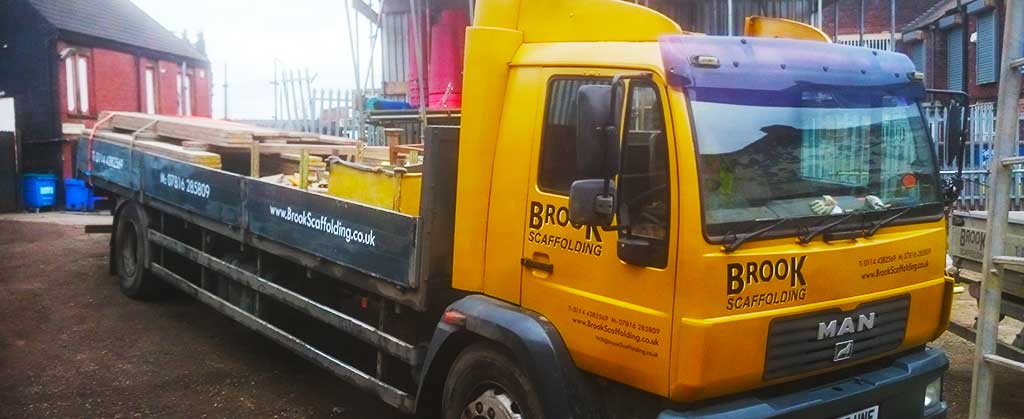 front distance corner view of brook scaffoldings largest scaffold truck on site with scaffolders removing scaffold as they need it