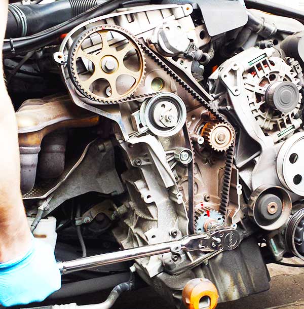 close up front view of a vehicle tinming cambelt showing the intricate pulley system and routing of the belt