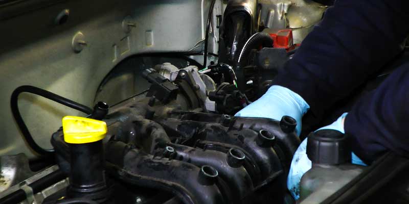 close up of a renault engine with a mechanic in bright blue gloves servicing it