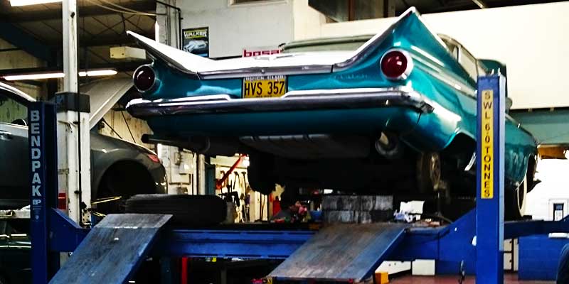 rear distance view of a classic american cadillac car on excels ramp ready for repairs to be carried out