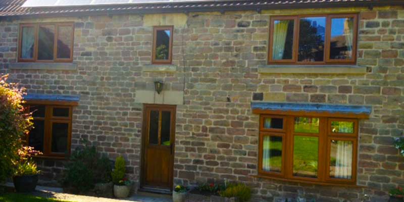 distance view of a sheffield bard conversion sporting real hardwood windows and doors that blend seamlessly with the buildings aged look