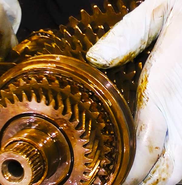 close up front view of a vehicle gearbox being reconditioned by an experts rubber gloved hands