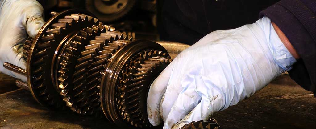 close up of a vauxhall gearbox layshaft in one of m and t transmissions specialists hands being checked for issudes like broken and chipped teeth