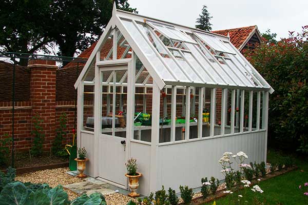 distance corner view of a stunning edwardian greenhouse in very light grey
