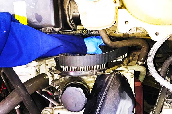 New Cam Belt Being Fitted close up view of a garage mechanic fitting a new timing cam belt to a volvo car engine