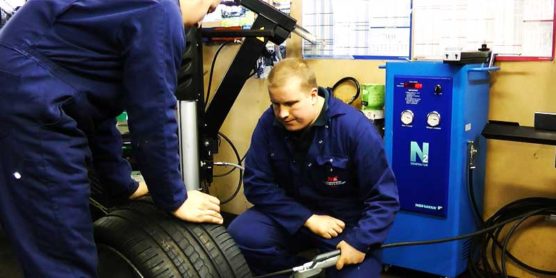 distance view of tyre fitters fitting new tyres to car wheels