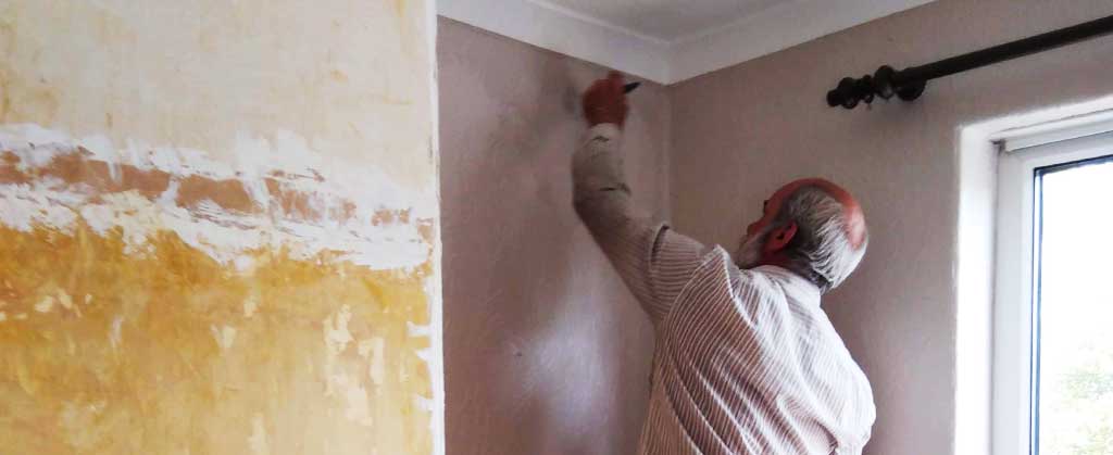 expert painter russ decorating a sheffield home up on a small stool cutting in the ceiling paint in white