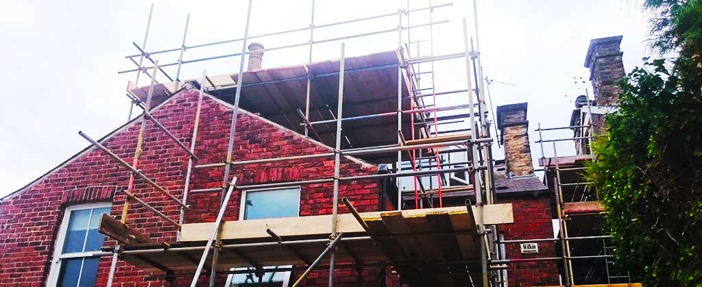 distance rear corner view of a home completly encased in scaffolding by brooks