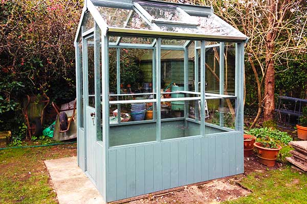 close up corner view of a victorian greenhouse in aqua blue